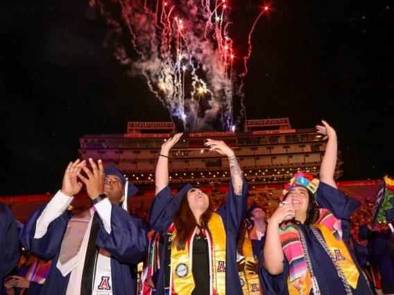 students celebrating during a fireworks display at commencement