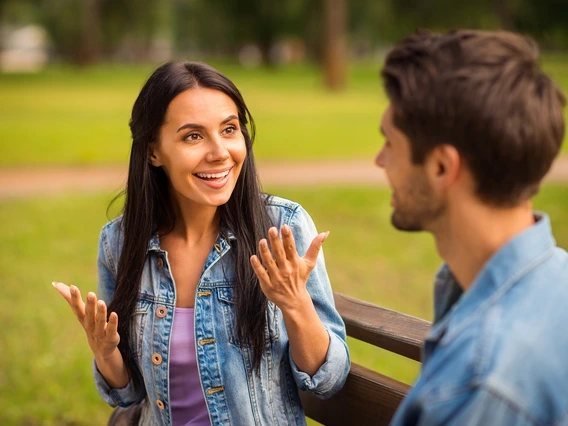 Woman talking to a man sitting on a bench