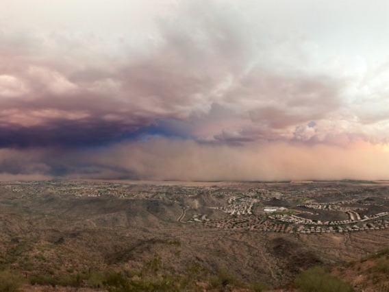 Clouds and a dust storm form over a desert landscape