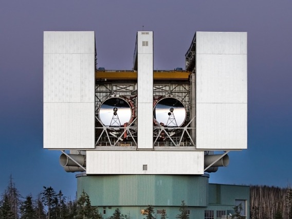 The two mirrors of the Large Binocular Telescope peer through the openings in the telescope&#039;s enclosure. 