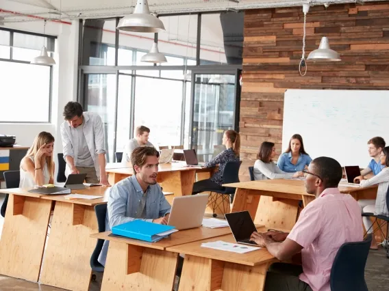 two people sitting at desks in an open office space and talking