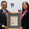 A man and a woman stand holding a plaque.