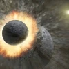 Two celestial bodies, riddled with craters, are depicted crashing into each other. The impact throws up a ring of fiery, molten rock and sprays debris far out into the surrounding space. 