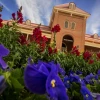 the facade of old main rising above a bed of blossoming flowers